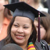 A student smiles while holding flowers received for her graduation from Augsburg.