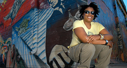 Keme Hawkins sitting in front of a large, urban mural.