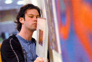 Zac Wooten hanging artwork along a vivid-colored wall.