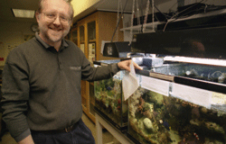 Bill Capman in front of coral reef tanks