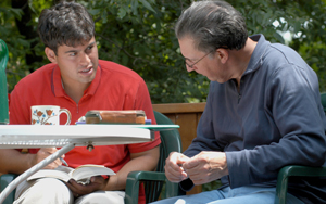 Prof. Markus Fueher and Alex Krantz studying outside on a patio.